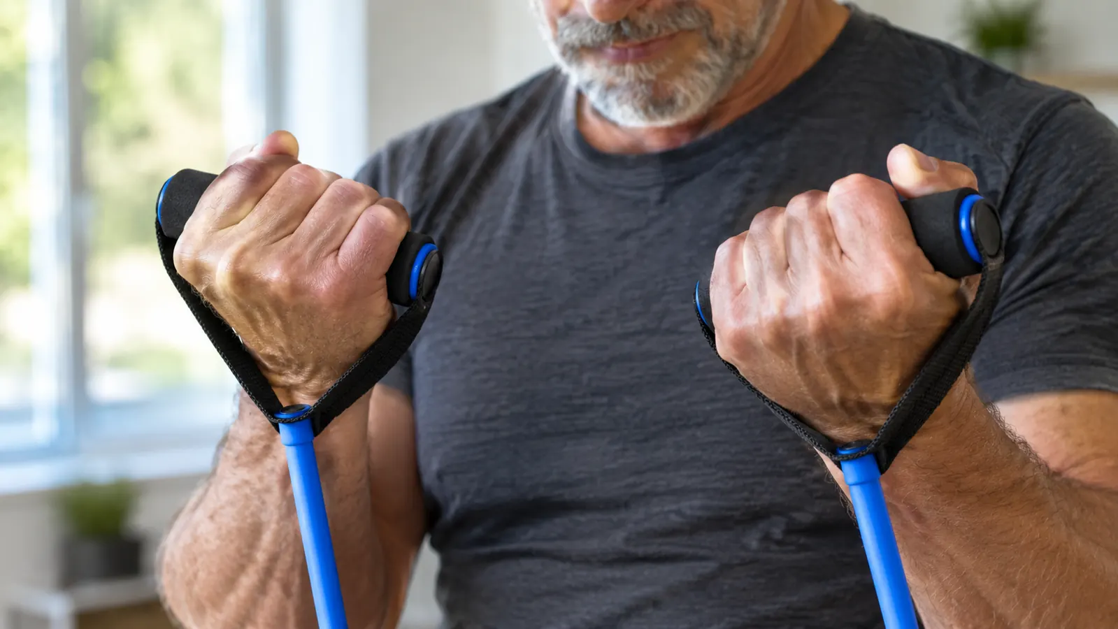 Close-up of hands gripping the padded handles of the resistance bands during a seated row